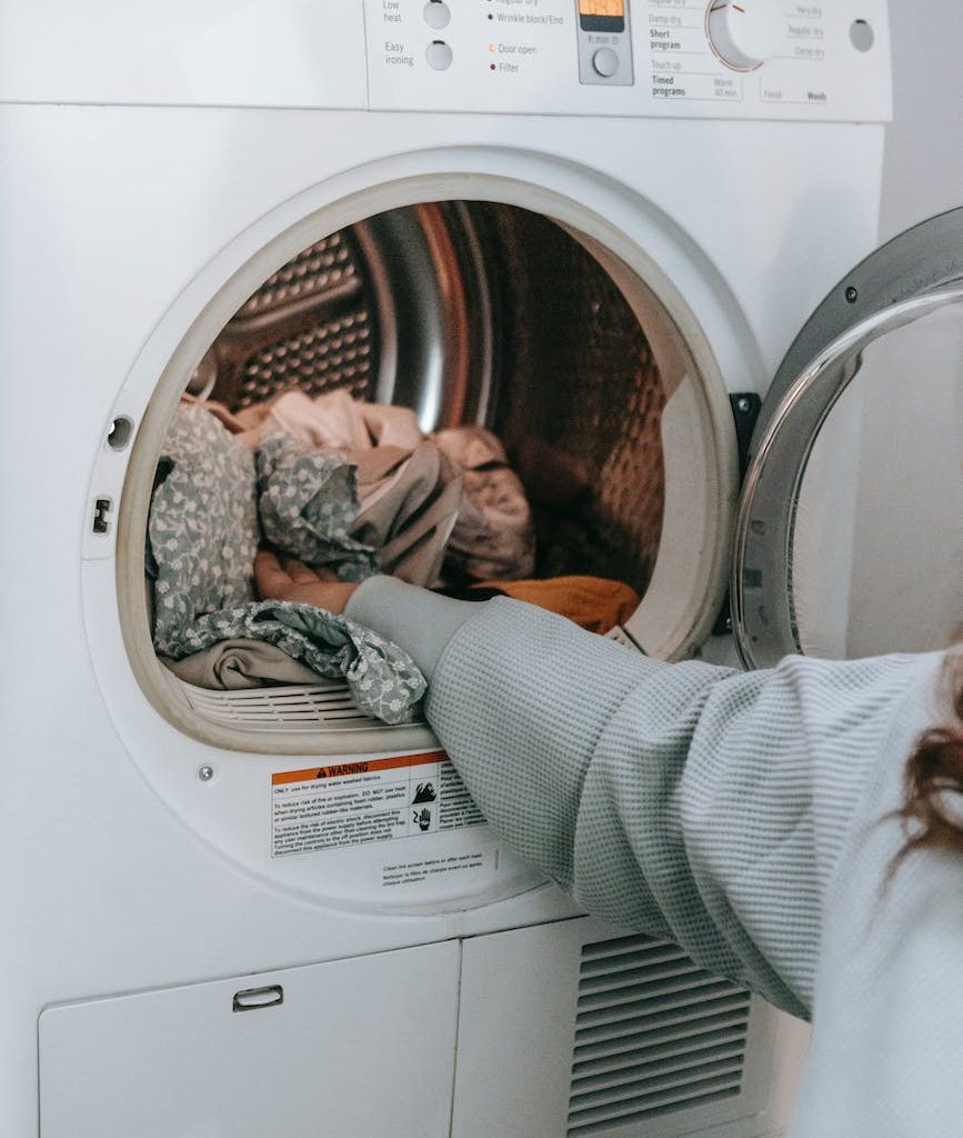 anonymous woman loading clothes in washing machine