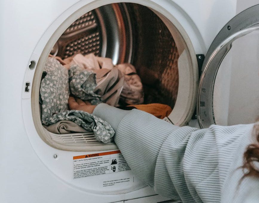anonymous woman loading clothes in washing machine