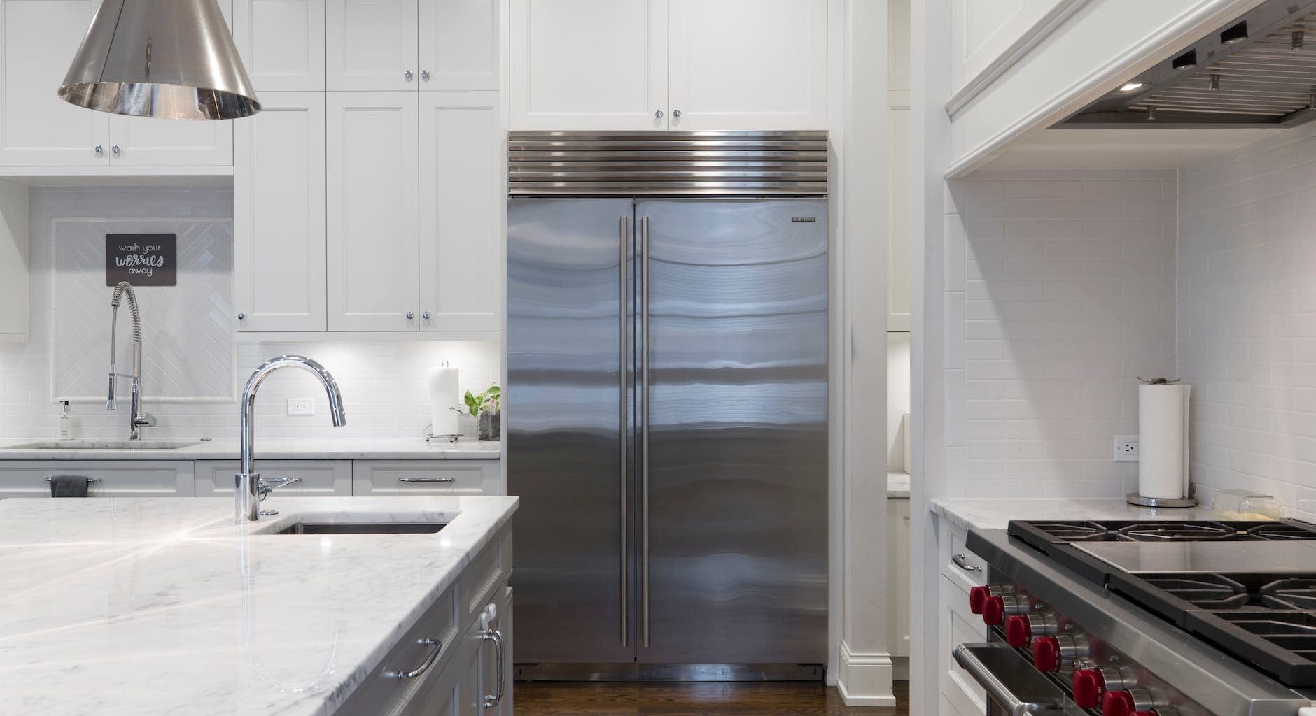 stainless steel refrigerator beside white kitchen cabinet